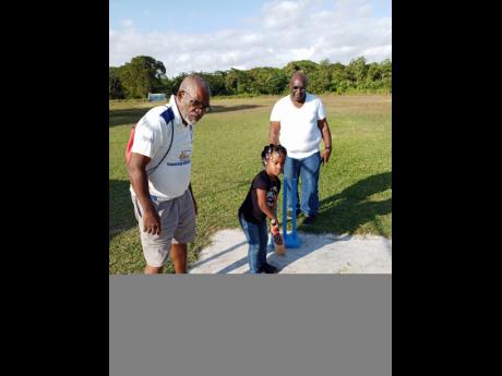 Coach Grantley Reid (left) takes a child through the rudiments of cricket while being watched by Westmoreland Cricket Association’s President Deltonio Williams during one of the training camps.