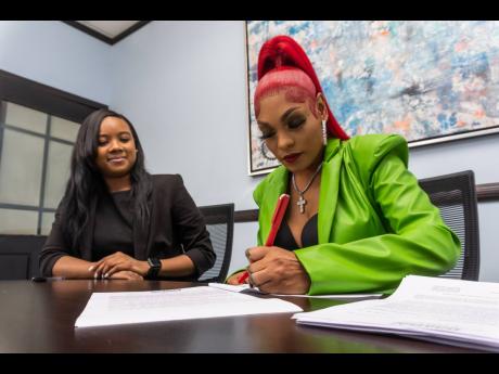 Attorney-at-law Rykel Chong (left) of Nigel Jones and Company oversees the signing of an album deal between recording artiste Sasique and Payday Records.