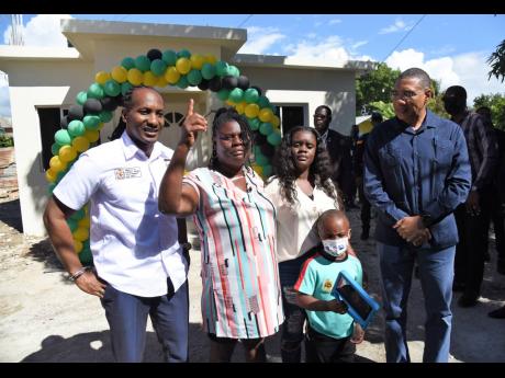 Moveta Clarke (second left) can hardly contain her excitement as she receives her new home from Prime Minister Andrew Holness (right). Clarke's house was burnt to the ground about two years ago and she recently suffered a stroke that affects her walking.  Looking on are Alando Terrelonge (left), member of parliament, St Catherine East Central, Kimberly McNeil, Clarke's daughter and Anthony Dacosta, Clarke's grandson. 