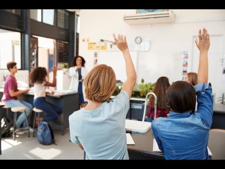 Pupils raising hands in a high school science lesson.
