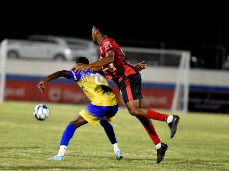 Arnett Gardens’s Earl Simpson (right) rides the back of Calorado Harding of Harbour View while they fight for the ball during their Jamaica Premier League match at the Ashenheim Stadium last night. Arnett won the match 1-0.