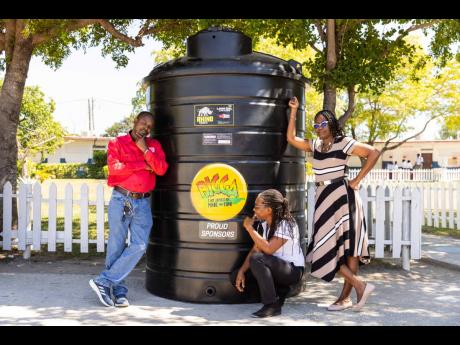 Senior staff members of Bridgeport High School, (from left) Malcolm Nelson, Paula Taylor, and Marcia Palmer, pose in front of one of the two 1,000-gallon water tanks presented to the school by Bigga last Friday.