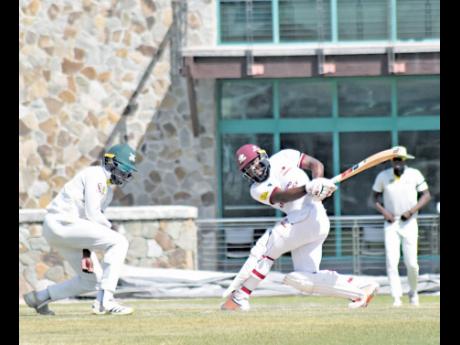 Leeward Islands Hurricanes captain Jahmar Hamilton (centre) plays a slug sweep while Jamaica Scorpions fielder Kirk McKenzie (left) takes evasive action, during their West Indies Championship match at Coolidge in Antigua yesterday.