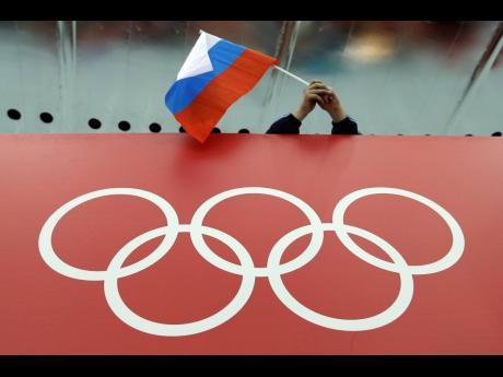 FILE - A Russian flag is held above the Olympic Rings at Adler Arena Skating Center during the Winter Olympics in Sochi, Russia, on Feb. 18, 2014. Russia and its ally Belarus have been invited to compete at the Asian Games in the next step to qualify athletes for next year’s Paris Olympics. The arrangement has been brokered by the International Olympic Committee.
