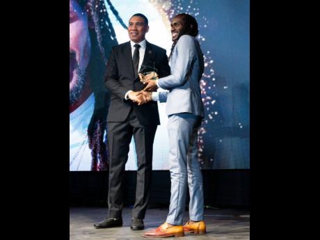 Prime Minister Andrew Holness (left) presents the Youth Award for music to Mariki Whyte.