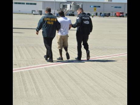 A Jamaican man being escorted by American law-enforcement officials after he was ordered extradited to face lottery scamming charges in the United States of America.