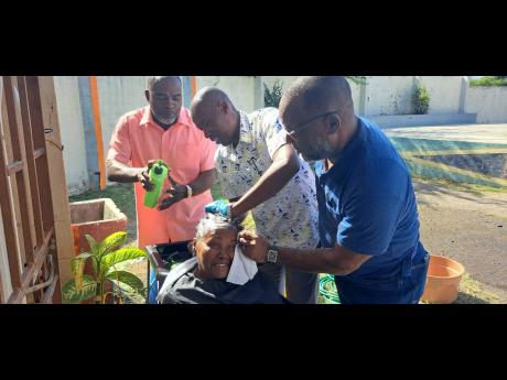 Portmore Mayor Leon Thomas (right) and Independence City Councillor Courtney Edwards (centre) wash the hair of a senior. Looking on is Fenley Douglas, councillor for the Waterford Division.