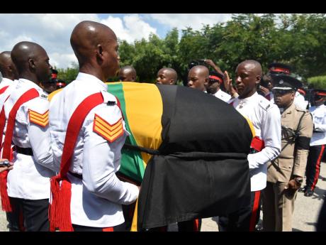 Pallbearers carry the body of former Commissioner of Police Lucius Thomas after his thanksgiving service at the Boulevard Baptist Church in St Andrew yesterday.