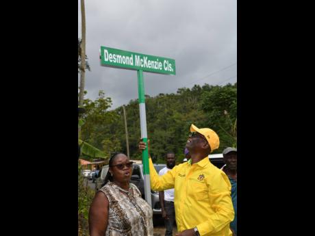 Credit: Contributed Minister of Local Government and Rural Development Desmond McKenzie (right) holds on to the Desmond McKenzie Close sign, following an unveiling ceremony held in Somerset, Manchester, last Friday. At left is councillor for the John’s Hall division, Manchester North West, Faith Sampson.
