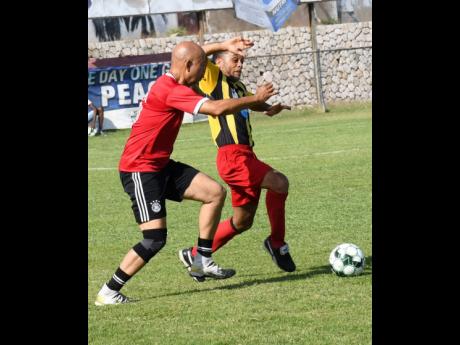Credit: Rudolph Brown Marshy Reds (right) of Christian Ambassadors and Lance Whittaker of Masters and Celebrities fight for the ball at the 41st Bob Marley Masters and Celebrities One Love football match at Anthony Spaulding Sports Complex on Wednesday.