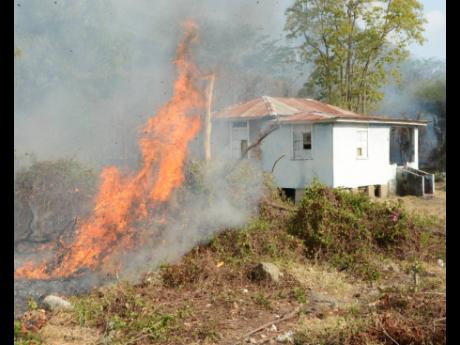 A bush fire in St Thomas threatens a house. 