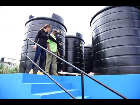 Minister of Local Government and Rural Development Desmond McKenzie and Member of Parliament for Portland Eastern Ann-Marie Vaz examine tanks at the newly commissioned water shop in Commodore district.

 