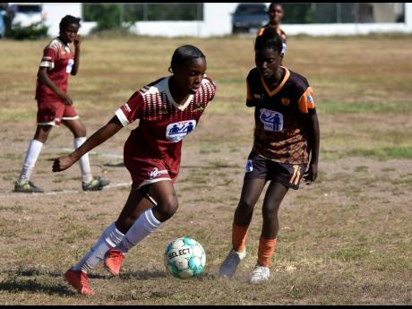 Credit: Kenyon Hemans Denham Town’s Natoya Atkinson (left) goes on one of her brilliant dribbles while being tracked by Tivoli High School’s Nathania Morris during their ISSA/TIP Friendly Schoolgirls’ football game at the Tivoli High School playing field yesterday.
