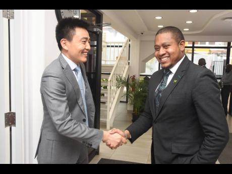 Huawei Jamaica CEO Bo Zhou (left) greets Floyd Green, minister without portfolio in the Office of the Prime Minister, at the tech company’s Kingston office last Thursday.
