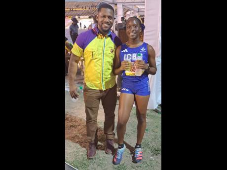 Father Jeremain Brown shares the joy of Najé’s silver medal in the Class Four girls’ 100 metres on Wednesday.