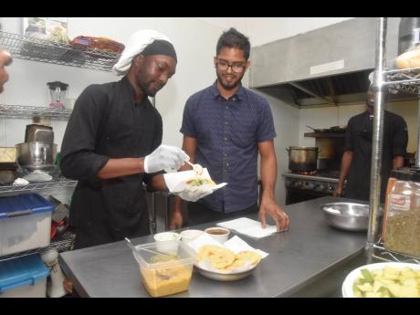 Wholesome Cafe owner Misir Ramberran (right) watches closely as chef Oniel Carty prepares a doubles.