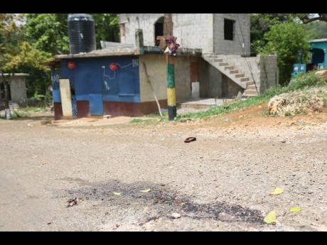 The bloodstained roadway outside a shop in Darlow, Mocho, Clarendon, where six persons were shot on Saturday night, two fatally. 