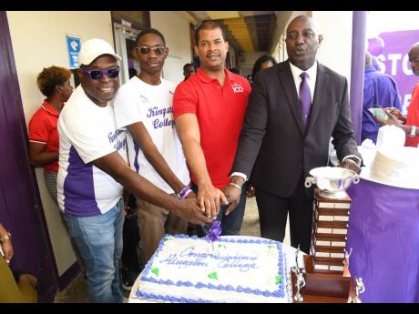 Credit: Rudolph Brown From left: Kingston College’s (KC) coach Leaford Grant, captain of the middle and long distance team Ainsley Campbell, chief executive officer of GK Foods Domestic at GraceKennedy Ltd Frank James and KC’s Principal Dave Myrie cut the celebratory cake during the Journey to 34 Champs devotion at the North Street campus yesterday.