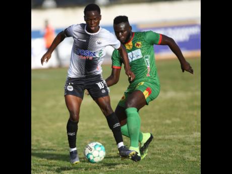 Cavalier’s Dwayne Atkinson is placed under pressure by Humble Lion’s Ricardo Campbell, during their Jamaica Premier League encounter at the Ashenheim Stadium yesterday. Cavalier won 1-0.