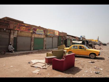 A man sits by shuttered shops in Khartoum, Sudan, on Monday. Sudan’s embattled capital has awoken to a third day of heavy fighting between the army and a powerful rival force for control of the country. 