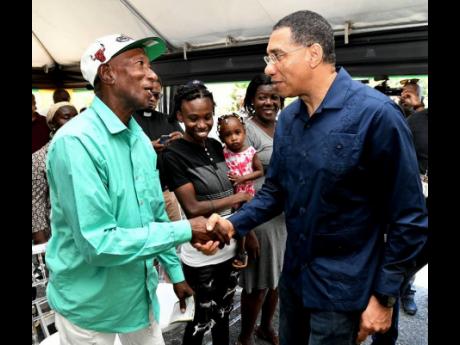 Prime Minister Andrew Holness (right) shakes hands with Lloyd White, a beneficiary under the New Social Housing Programme (NSHP), during the official handover of three housing units at Goodwin Park Road in Central Kingston. Looking on are the other beneficiaries, Leisha Brown (second left), who is holding her daughter, Mishka; and Lesa Brown.

 