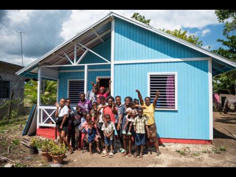 Melita Parkinson (centre, background), her children and grandchildren, celebrate her new home in Little London, Westmoreland. The house was donated to the family by Boom Energy Drink through Food For The Poor. Boom made the donation in January through its recently launched corporate social responsibility campaign, Boom with Love. 
