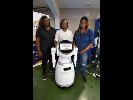University of Technology (UTech) students (from left) Dayjaney Pringle (left), Carlishe Nicholson and Shanice Facey stand with their robot friend at the Jamaica Constabulary Force 2023 Quality and Technology Expo at the National Arena on Thursday. Facey believes the robot can be utilised by the police to handle some tasks.