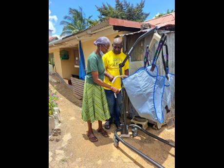 Credit: Rasbert Turner President of the Harris Foundation, Michael Harris, shows Joan Archibald how to use of the hydraulic lift that has been donated to her family to assist in taking care of their 57-year-old son, Patrick.
