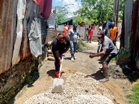 People’s National Party candidate for the Duhaney Park Division in the Kingston and St Andrew Municipal Corporation Michelle Thomas helps to mix aggregate for the wall’s construction.