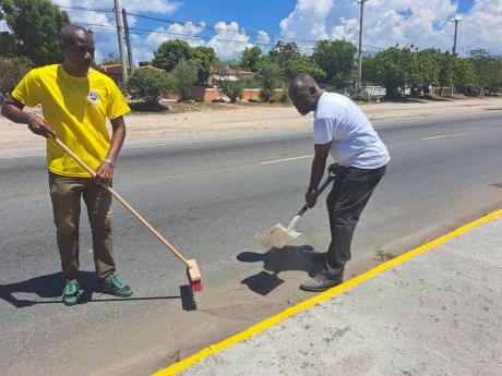 Portmore Mayor Leon Thomas (left) and Councillor of the Independence City Division, Courtney Edwards, painting sidewalks along George Lee Boulevard on Labour Day. 