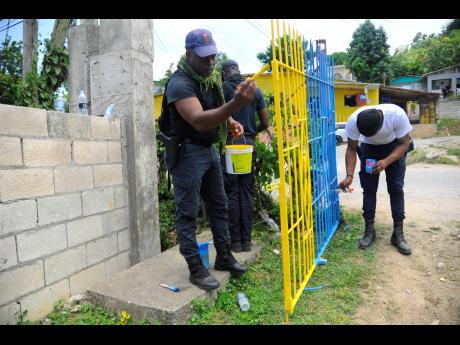 Members of the security forces make sure the school gate is looking good as new.