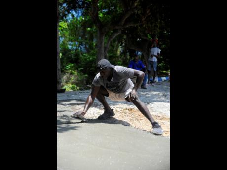 Carlton Roberts from Pimento Walk, a neighbouring community, settles the concrete to pave the entrance of Parry Town Primary School.