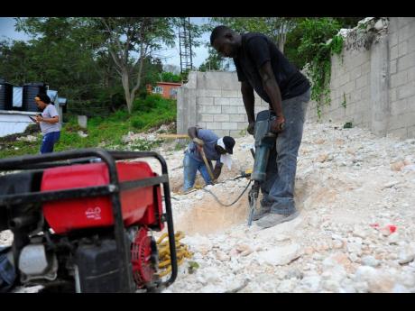 Omar Black uses a power tool to break through the rocky surface at the site. 