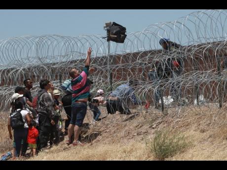 FILE - Migrants cross a barbed-wire barrier at the US-Mexico border, as seen from Ciudad Juarez in Mexico on May 11.  (AP Photo/Christian Chavez, File)