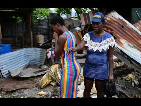 Credit: Gladstone Taylor Angela Williams (right) and her daughter, Keisha Williams, stand in front of their house, which was severely damaged after a Jamaica Defence Force vehicle crashed into it at Barbados Road, Waterhouse, St Andrew, on Friday.