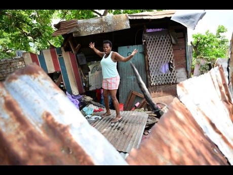 Credit: Gladstone Taylor Pamela Hassock recounts the terrifying sight of a Jamaica Defence Force vehicle crashing into this house in Waterhouse on Friday.