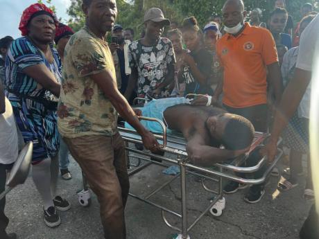 People transport an injured person after rescuing him from a house that collapsed after an earthquake in Jeremie, Haiti, yesterday.
