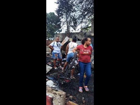 Sedden Brown (left) and sister Danielle Bent (right) inspect the rubble that was once their clothing store in Spanish Town, St Catherine. 