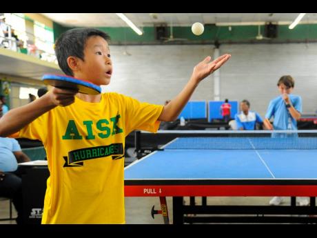American International School of Kingston’s (AISK) William Lei (left) watches the ball intently as he serves to Hillel Academy’s James Rosen during the boys’ team final of the Prep and Primary table tennis tournament at Excelsior High School Auditorium on Friday. Lei won 3-0 with scores of 11-4, 11-5, 11-6, but AISK lost the title 3-2 to Hillel.