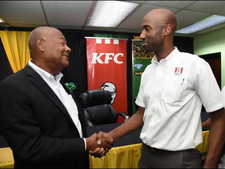 Michael Ricketts (left), president of Jamaica Football Federation (JFF), says thanks to Andrei Roper, brand manager, Restaurants of Jamaica, after getting a sponsorship cheque for $6 million towards the Reggae Girlz trip to the 2023 FIFA Women’s World Cup at the JFF office in New Kingston yesterday.