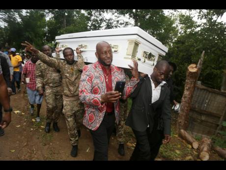 Pallbearers carry the casket containing the body of Merciless to his final resting place in Turners, Clarendon.