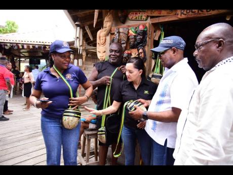 Minister of Tourism, Edmund Bartlett (second right), examines craft items made by business operator in the Port Antonio Craft Village, Girvan Rhoofe (second left), during the recent destination assurance tour of sections of Portland where he and other representatives met with parish stakeholders. Sharing the moment are (from left) Permanent Secretary in the ministry, Jennifer Griffith; Member of Parliament, Portland East, Ann Marie Vaz; and Mayor of Port Antonio, Councillor Paul Thompson. 