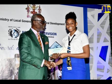 Minister of Local Government and Community Development, Desmond McKenzie (left), presents Board of Supervision Top Achiever in the 2022 Caribbean Advanced Proficiency Examination, Chelsia Reynolds, with a financial grant and a plaque. The presentation was made during the Board’s awards ceremony held recently at the Spanish Court Hotel in New Kingston.

 