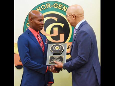 Lynworth Brown receives his  Governor-General’s Achievement Award for excellence in Community Service from Governor General Patrick Allen during the National Presentation Ceremony, held at King’s House, St Andrew, last Thursday. 