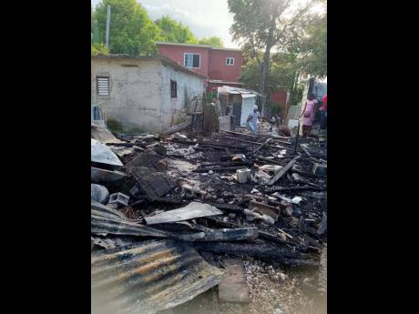 Residents look at the rubble of the home in Mammee Bay, St Ann, which was destroyed by fire.