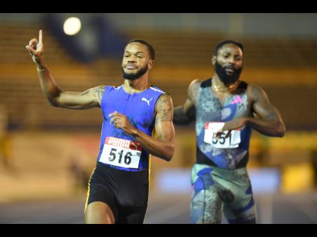 Andrew Hudson (left) celebrates winning the men’s 200 metres ahead of Rasheed Dwyer during the National Senior and Junior Championships at the National Stadium yesterday. Hudson clocked 20.11 seconds, while Dwyer was second in 20.26.
