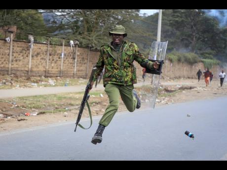 A policeman jumps as he tries to avoid a tear gas thrown back towards the police by protesters in the Mathare neighbourhood of Nairobi, Kenya, yesterday. Kenyans angered by the rising cost of living were back protesting on the streets of the capital.