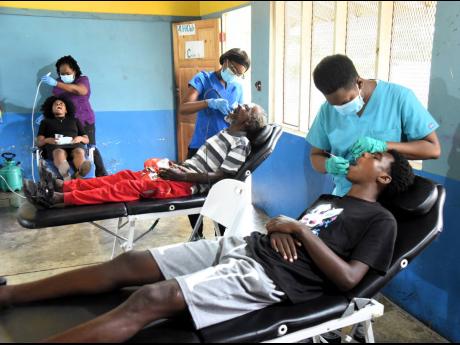 Dental hygienists tend to residents of Old Harbour Bay and its environs during the Jamaica Energy Partners ninth annual health, dental and wellness fair held at the Old Harbour Bay Primary School in St Catherine last Friday.