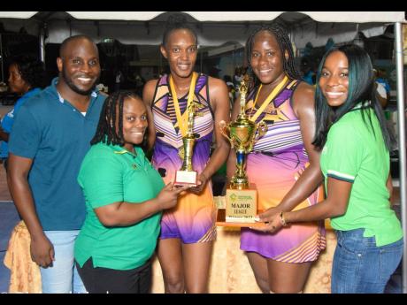 Credit: Contributed Netball Jamaica’s President Tricia Robinson (second left) hands Upsetters A’s Paula Thompson the Most Valuable Player trophy after they won the Major League final of the Supreme Ventures Netball League, with that being presented to co-captain Tracy-Ann Robinson (second right) by Sponsorship and Events Officer of Supreme Ventures Limited, Gabrielle Waite (right) at the Leila Robinson Courts on Saturday. Dwayne Gutzmer, chair of the local organising committee for the qualifiers, is at left.