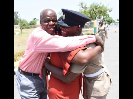 Credit: Ian Allen Top recruit Romaine Richards (right) hugs his parents, George and Arlene Richards, after the Passing Out Parade of the Jamaica National Service Corps at the Polo Grounds, Up Park Camp, last Friday.
